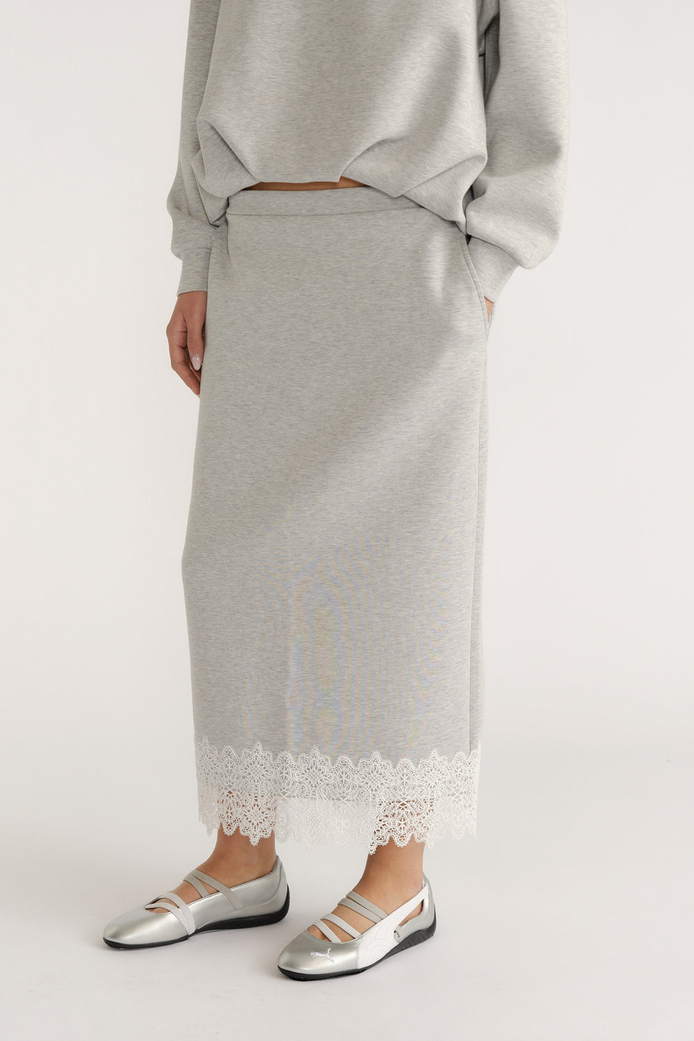 Grey midi skirt with delicate white lace trim paired with metallic silver flats for a chic, relaxed look