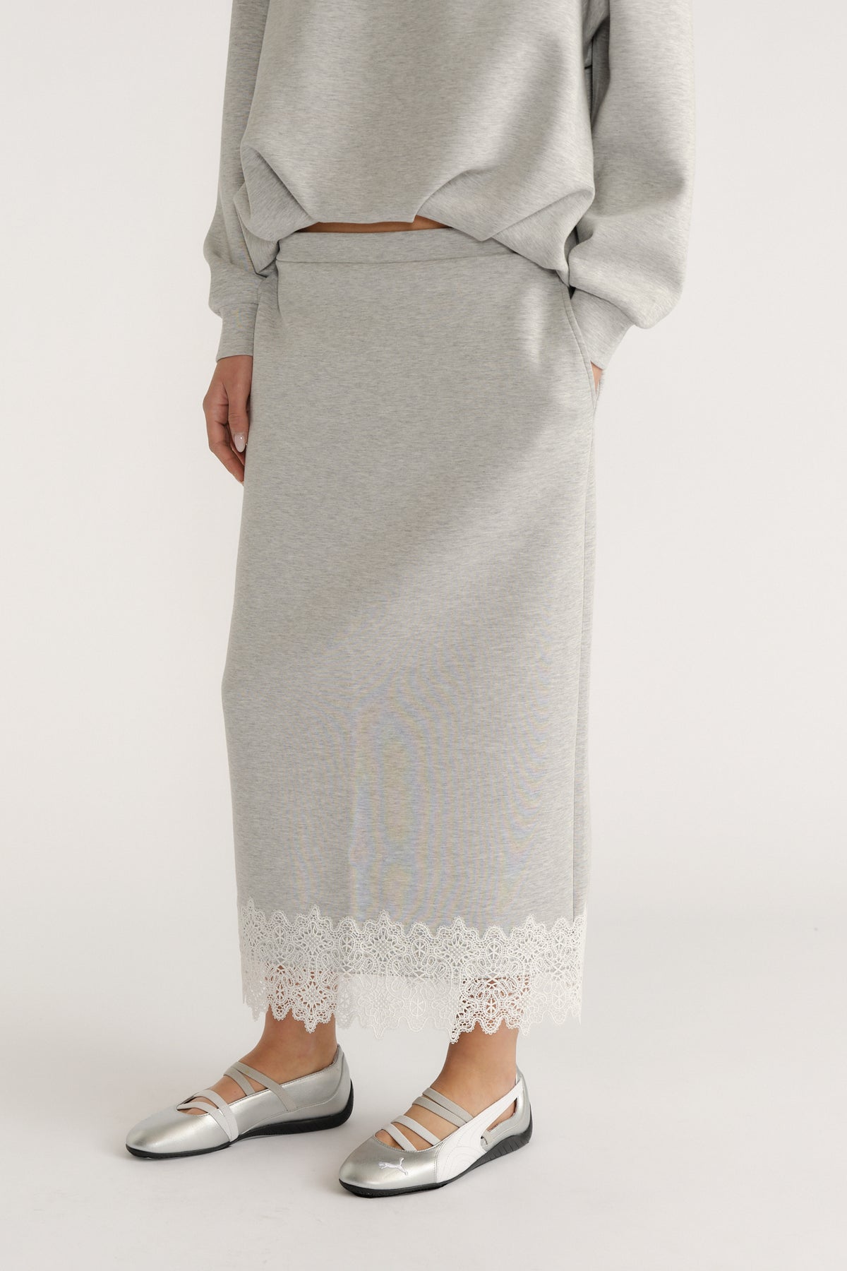 Grey midi skirt with delicate white lace trim paired with metallic silver flats for a chic, relaxed look