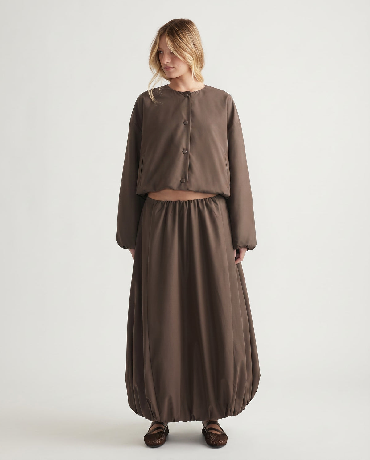 Woman wearing a relaxed fit brown crop jacket with matching voluminous skirt and soft flat shoes for effortless style