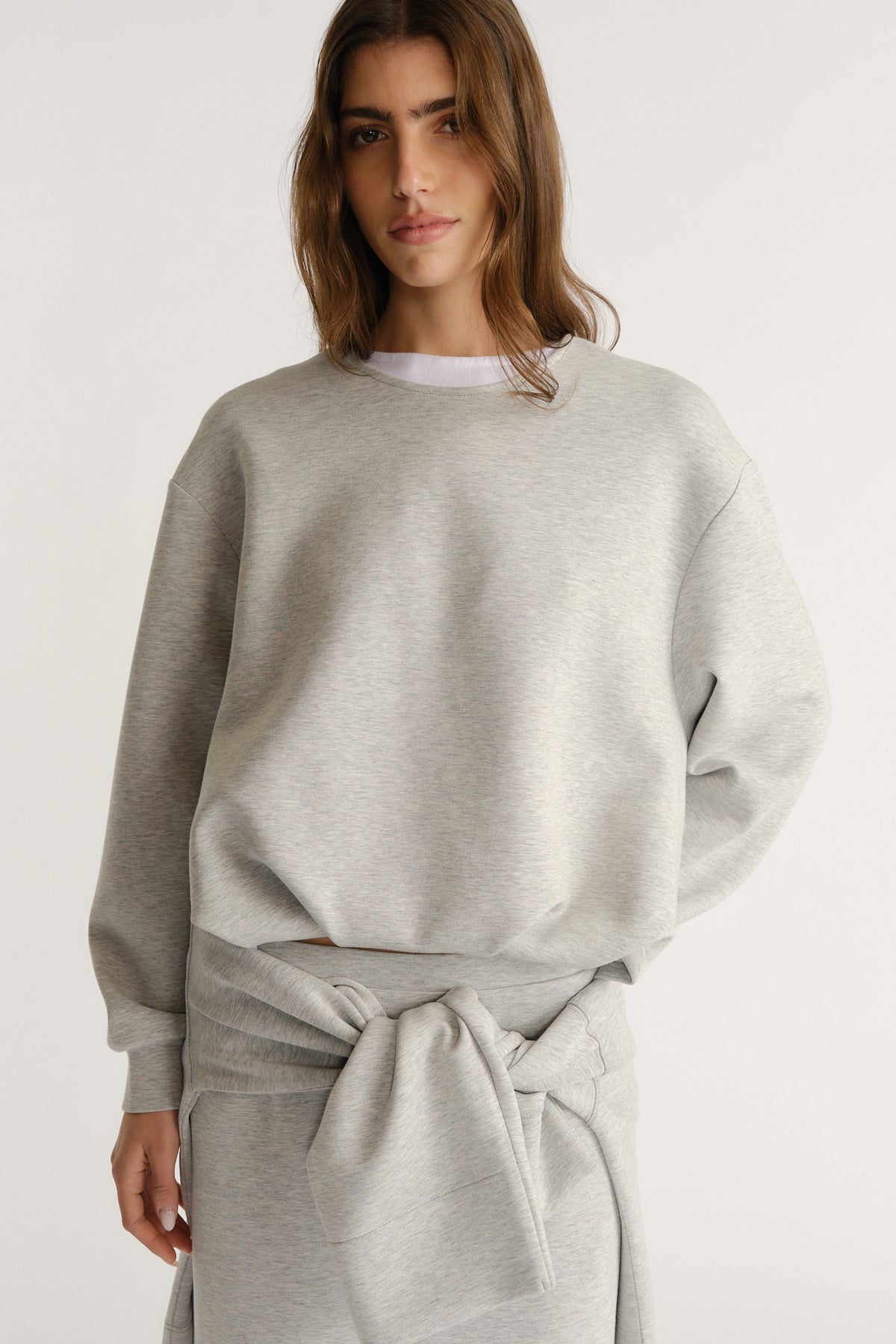Light grey relaxed-fit sweatshirt styled with a matching tied sweatshirt for a cozy, modern layered look