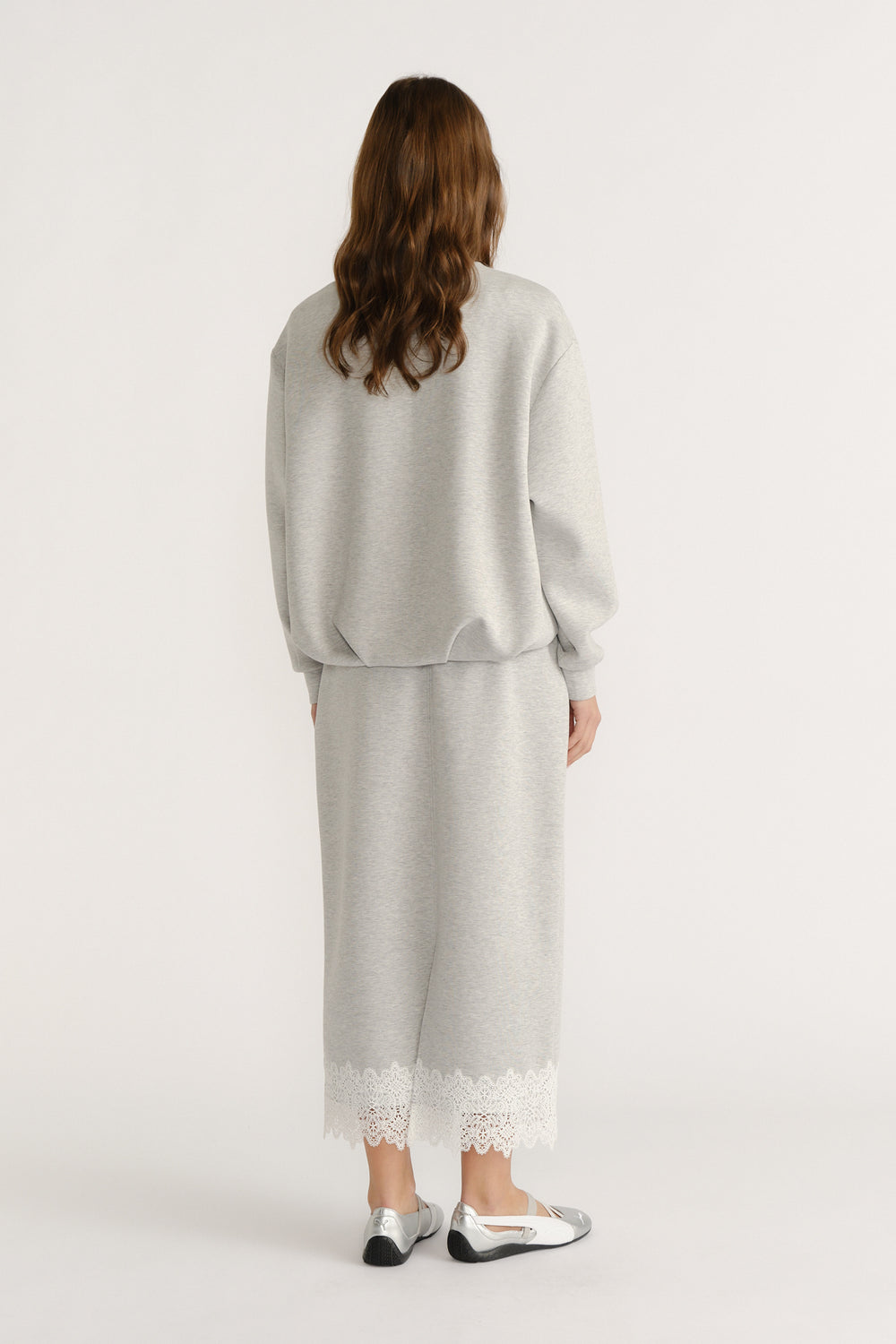 Woman wearing a relaxed light grey lounge set with lace-trimmed hem and metallic silver flats for an effortless look