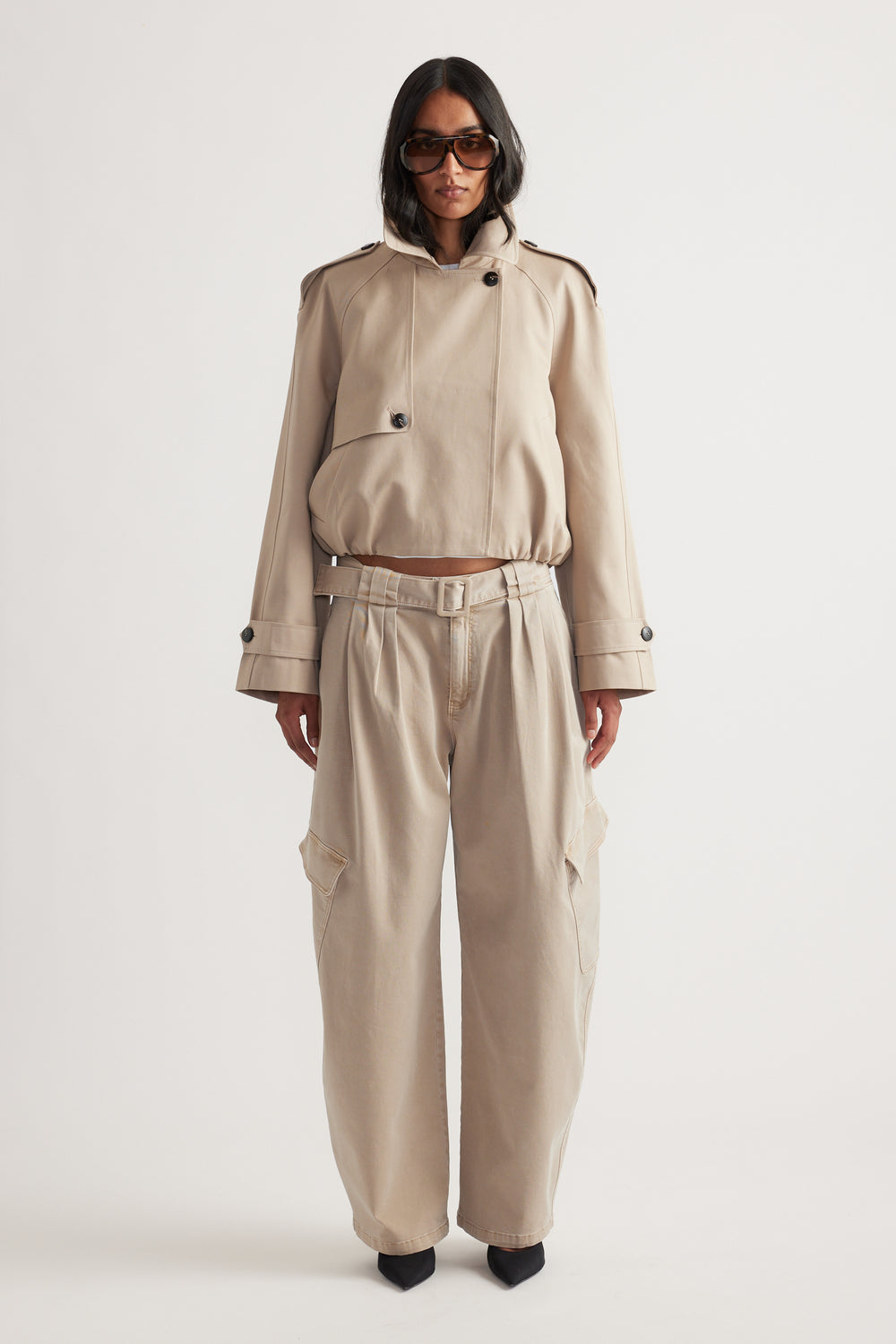 Woman wearing light beige belted balloon cargo pants paired with a matching cropped jacket and black pointed heels