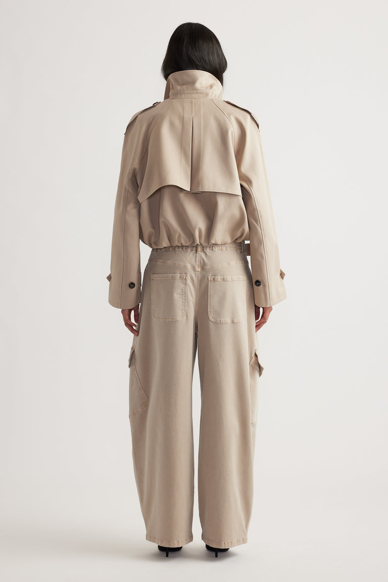 Woman wearing high-waisted wide-leg cargo pants in a neutral tone paired with a cropped trench jacket, shown from behind