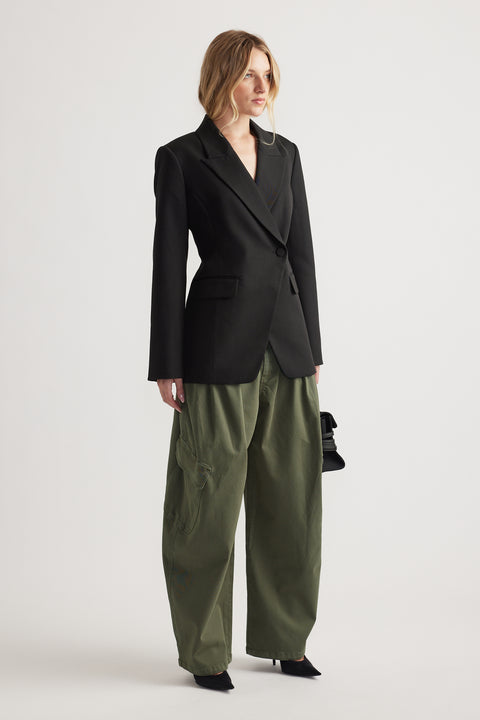 Woman wearing a tailored black blazer paired with loose-fitting olive cargo pants and black pointed heels