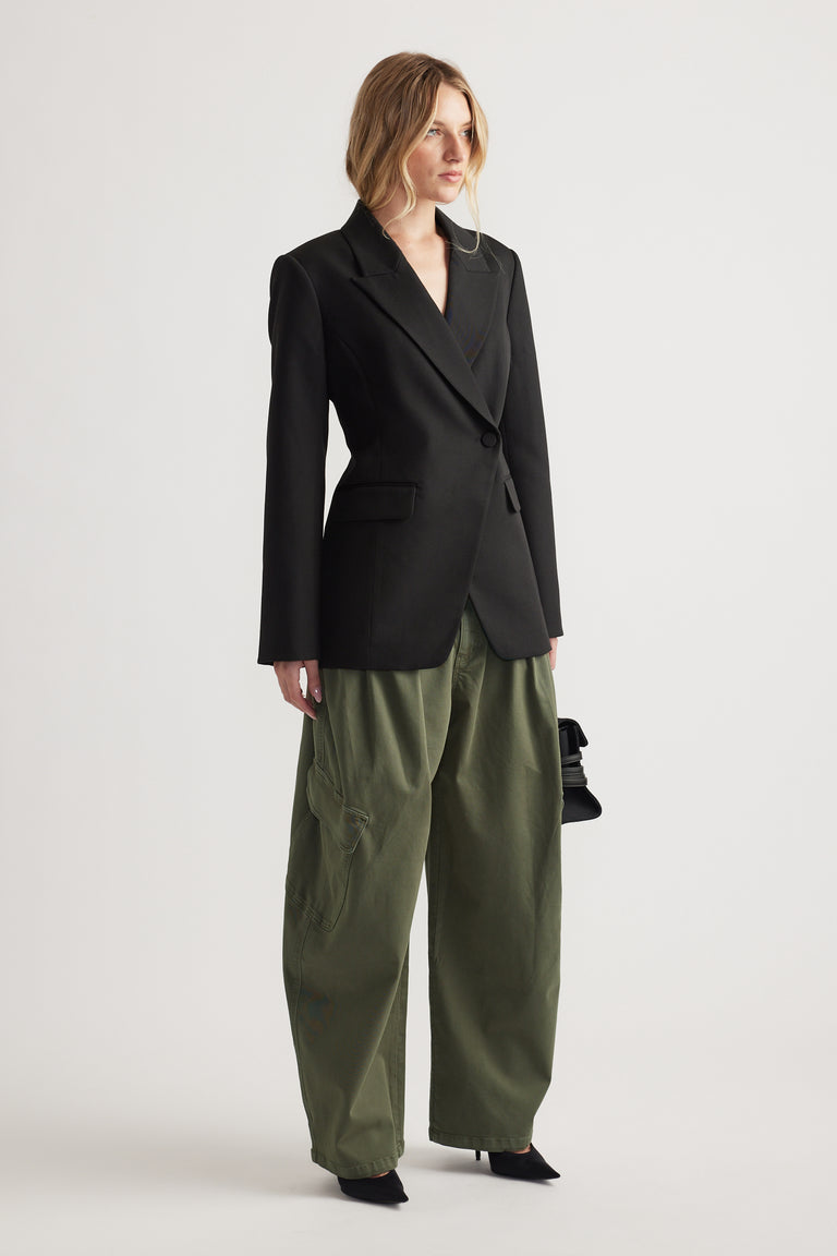 Woman wearing a tailored black blazer paired with loose-fitting olive cargo pants and black pointed heels