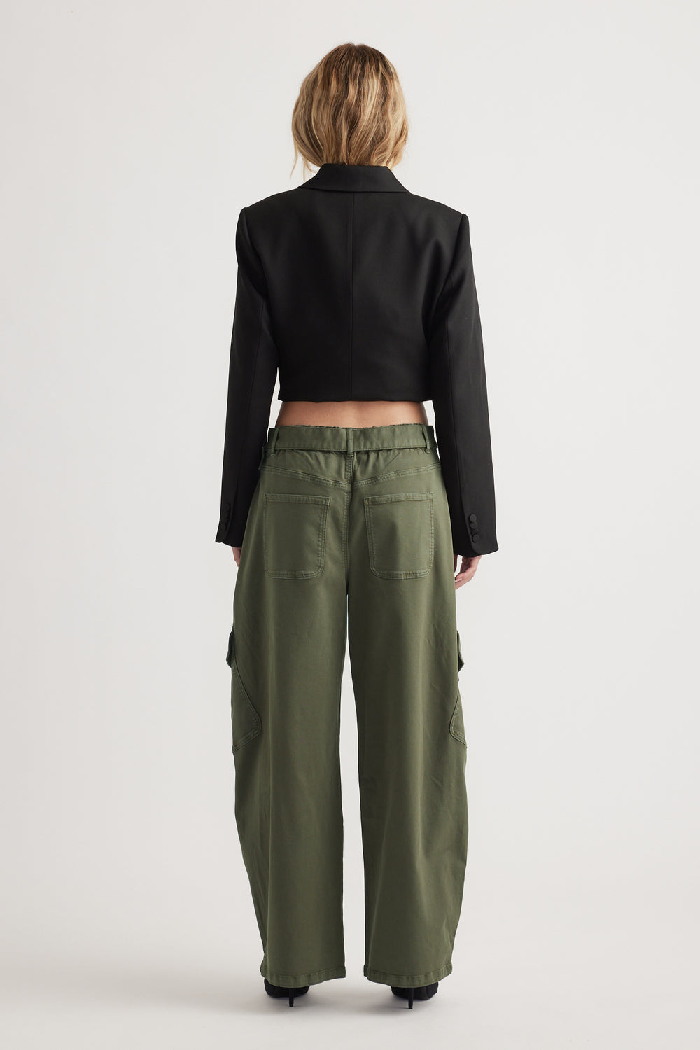 Back view of woman wearing relaxed olive green balloon cargo pants paired with a cropped black blazer jacket
