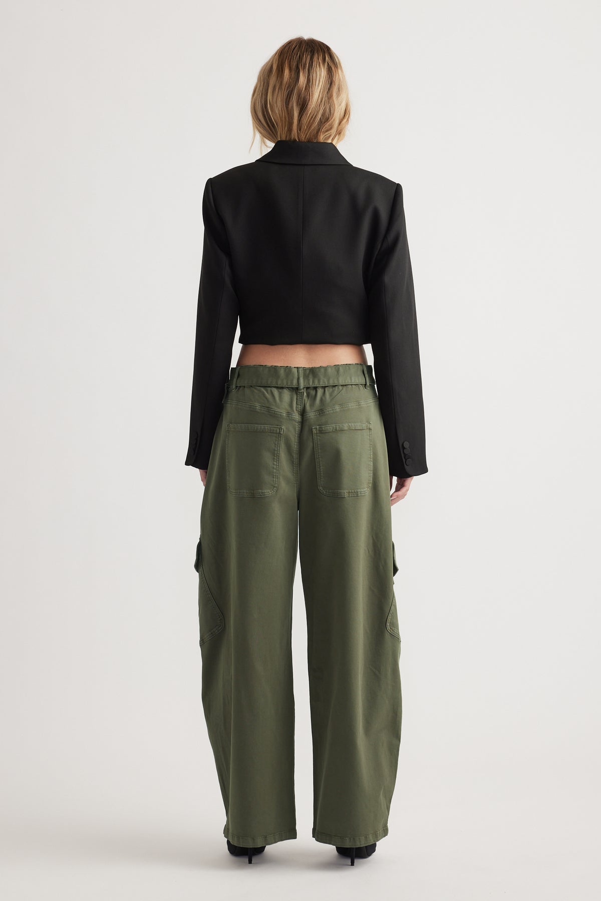 Back view of woman wearing relaxed olive green balloon cargo pants paired with a cropped black blazer jacket