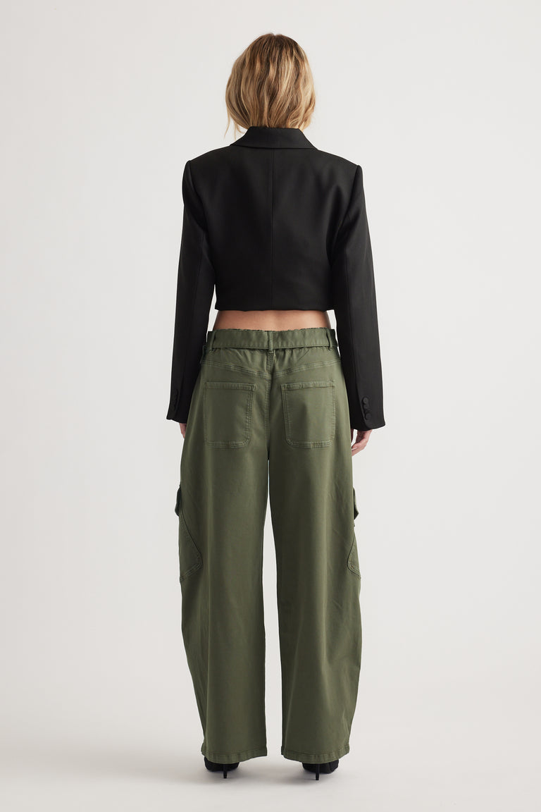 Back view of woman wearing relaxed olive green balloon cargo pants paired with a cropped black blazer jacket