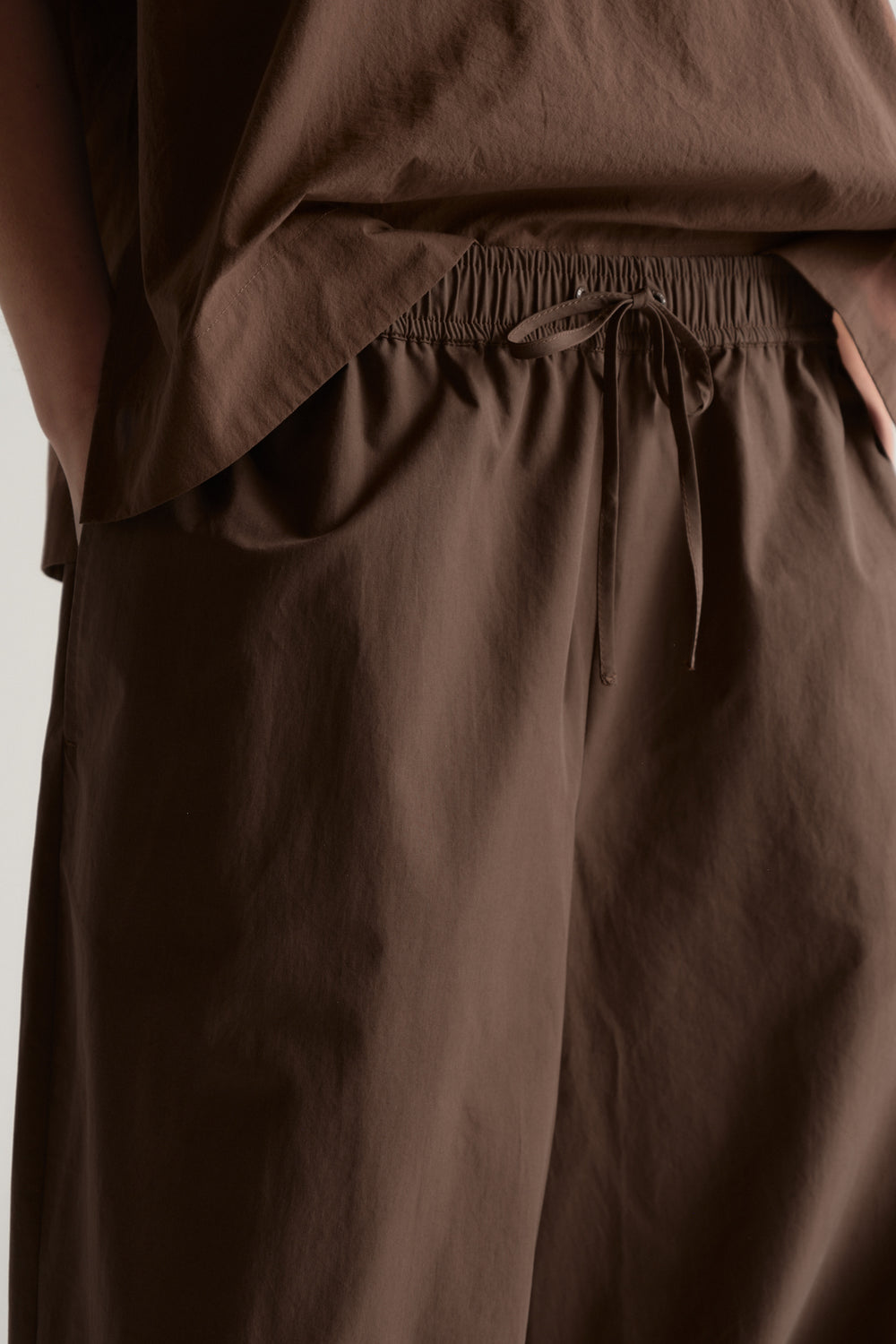 Brown barrel leg pants with an elasticated drawstring waist and relaxed fit