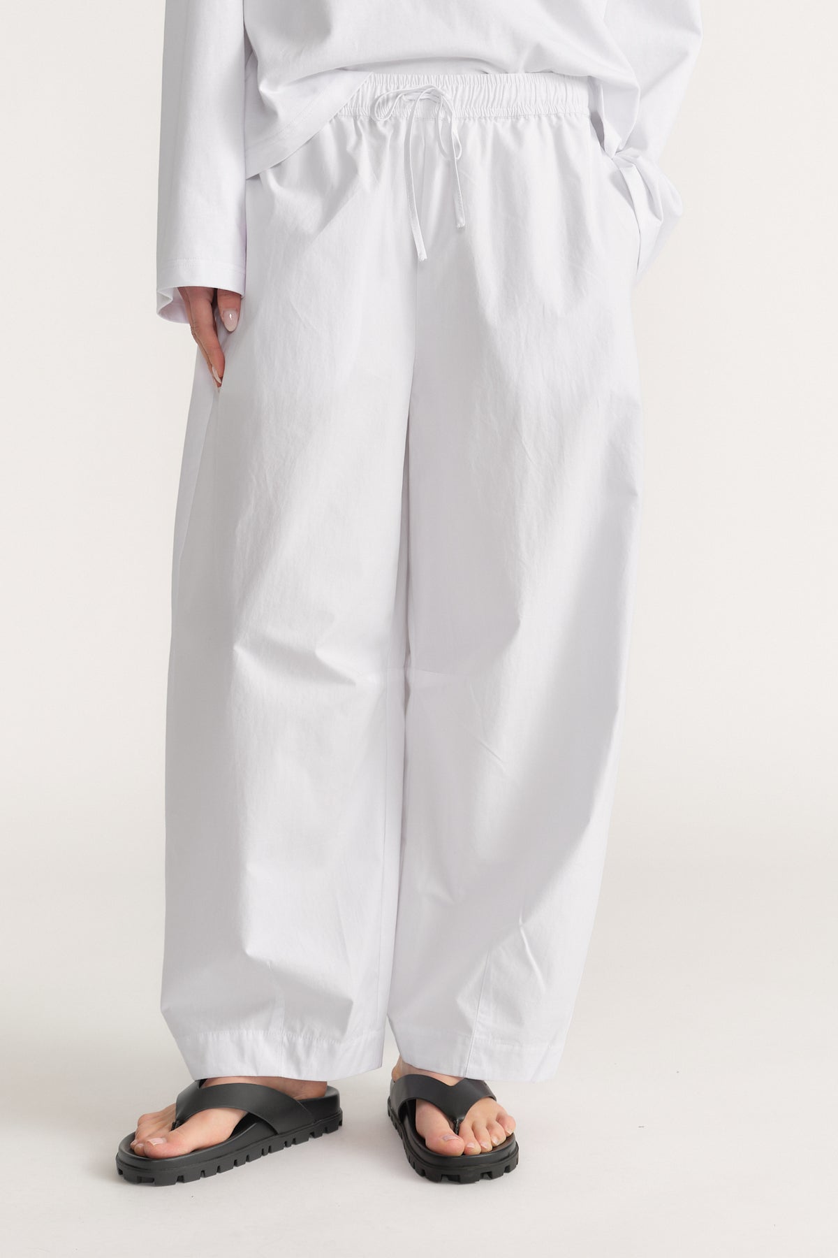 Woman wearing white elastic waist barrel leg pants with black sandals