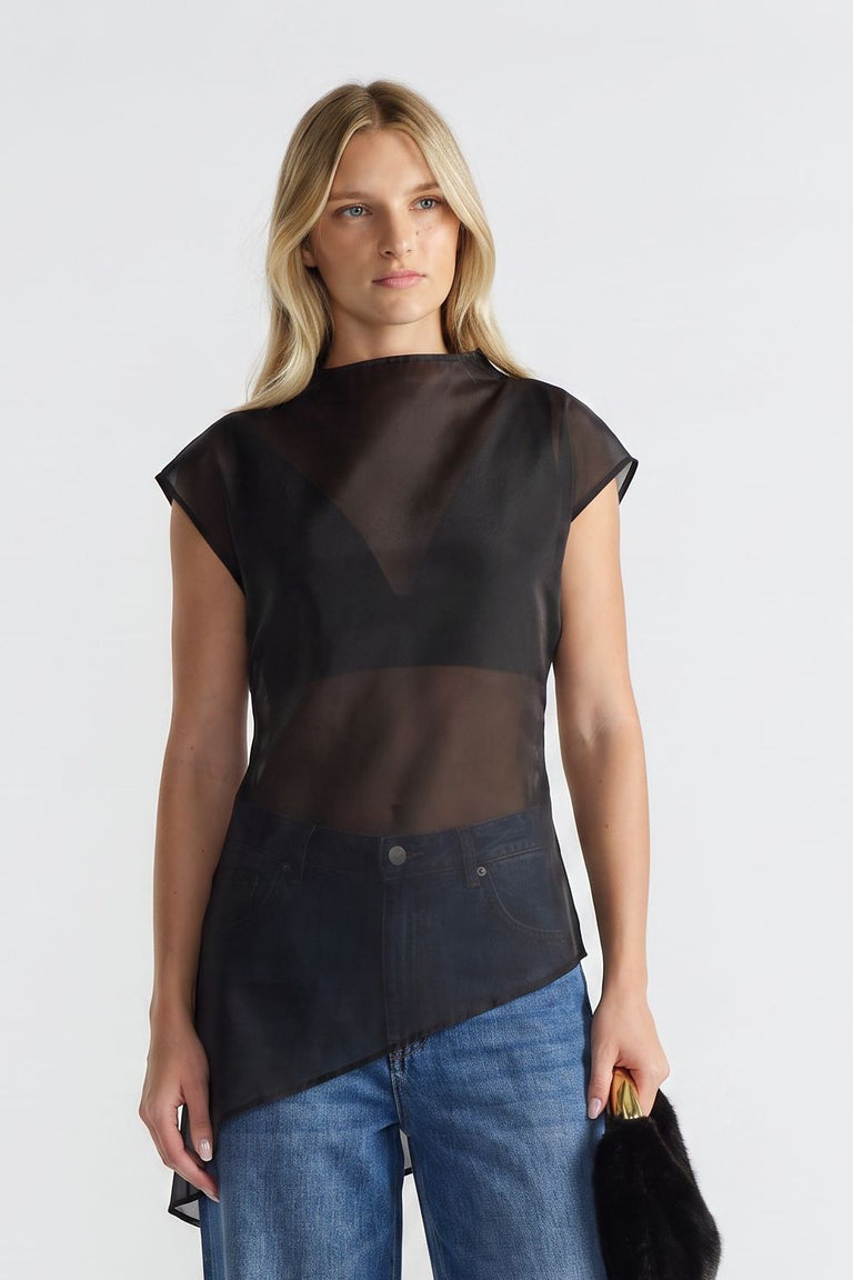 Woman wearing a black sheer sleeveless high neck top with an asymmetric hem and blue jeans
