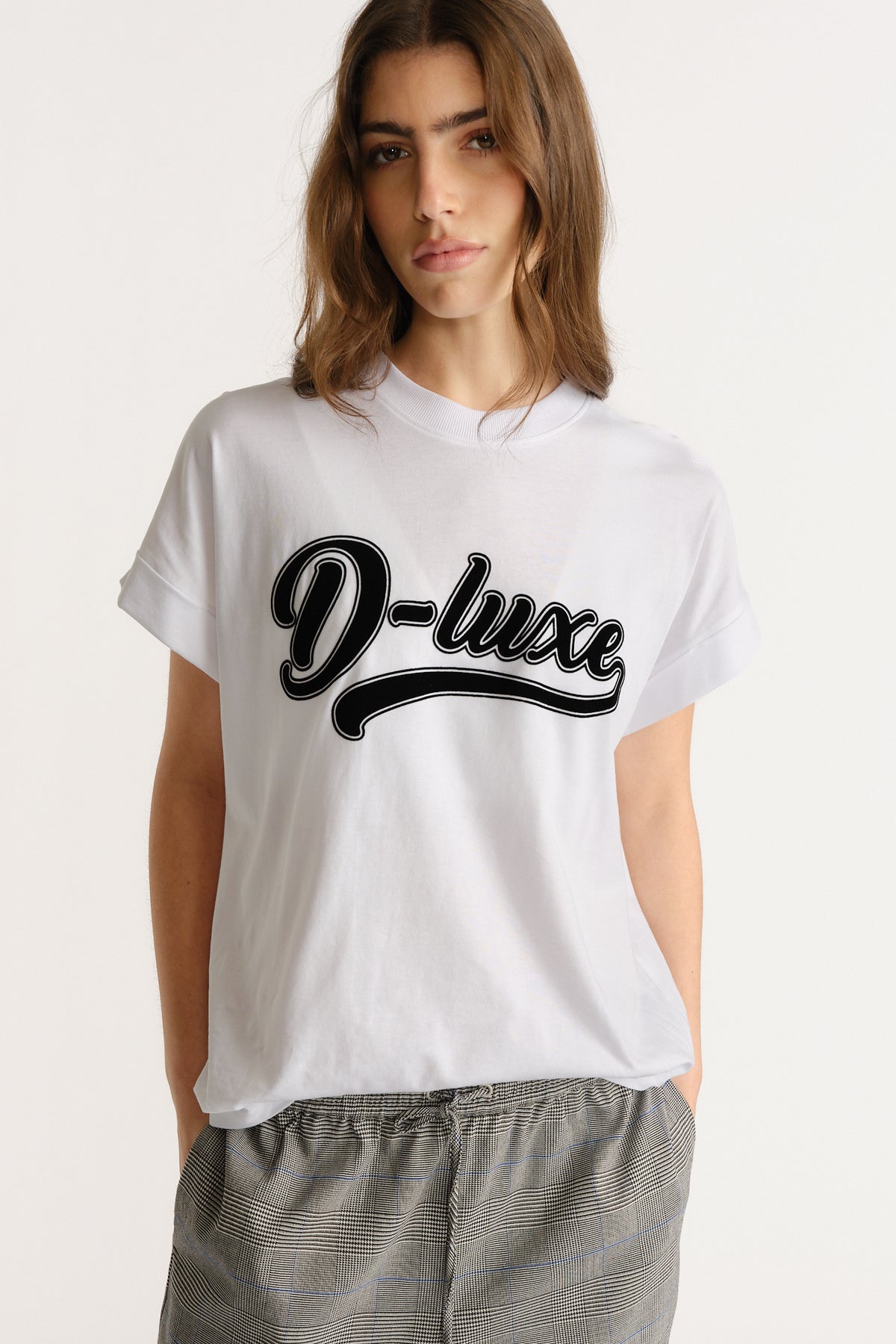 Woman wearing a relaxed white tee with bold script print paired with casual checked trousers for an easy everyday look.