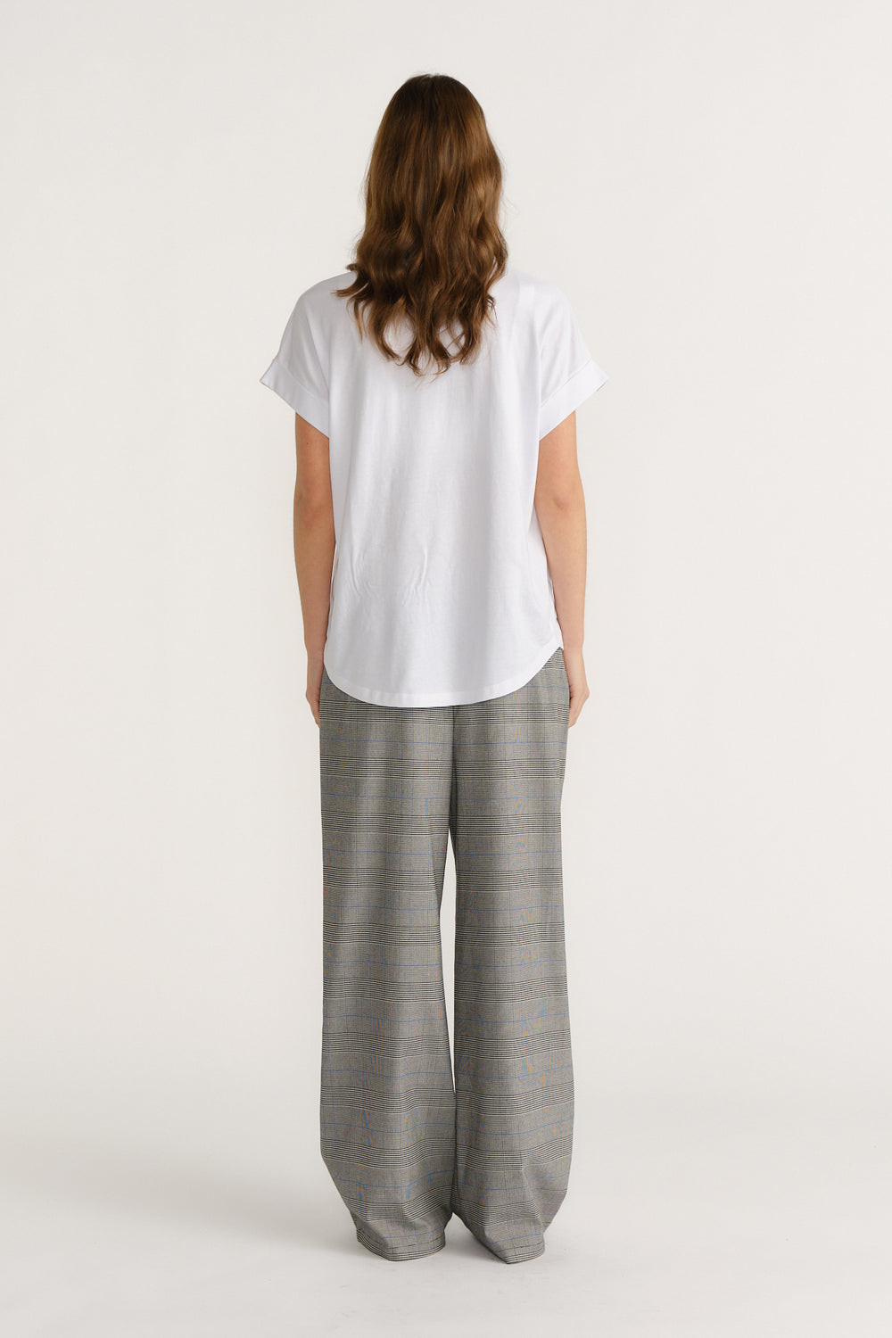 Woman wearing relaxed checked wide-leg trousers paired with a loose white tee for a stylish, easygoing look.
