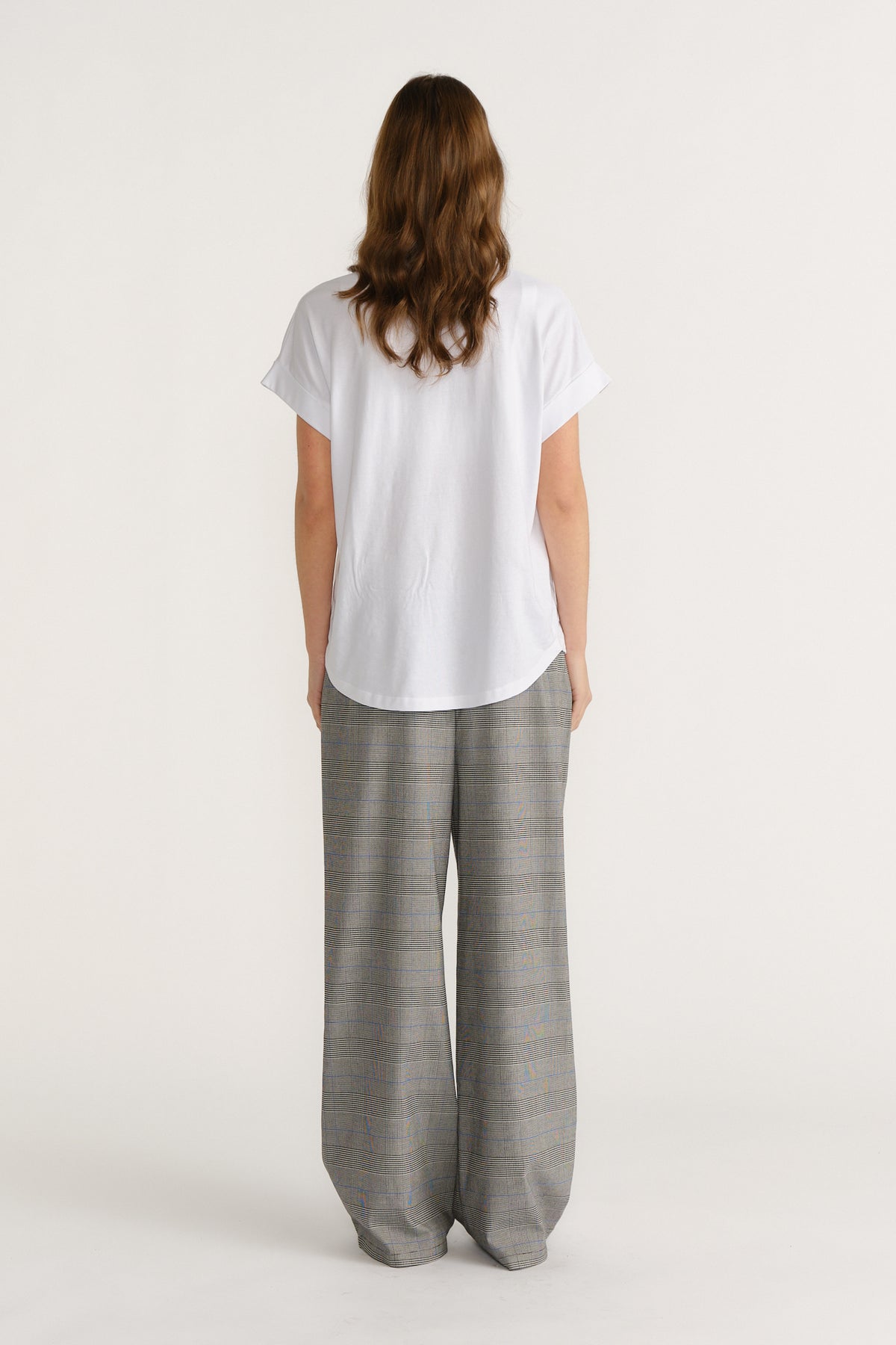 Woman wearing relaxed checked wide-leg trousers paired with a loose white tee for a stylish, easygoing look.