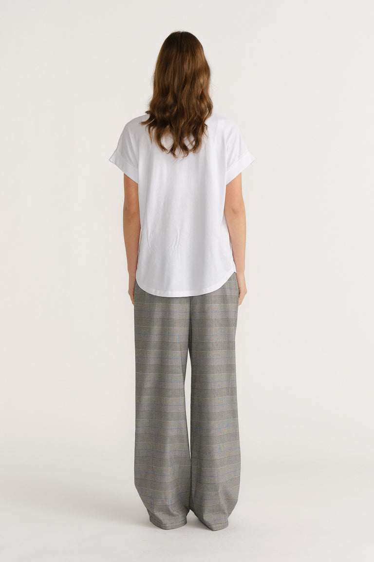 Woman wearing relaxed checked wide-leg trousers paired with a loose white tee for a stylish, easygoing look.
