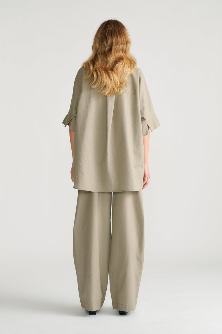 Woman seen from behind wearing sage green relaxed wide-leg pants with a loose matching tunic top.