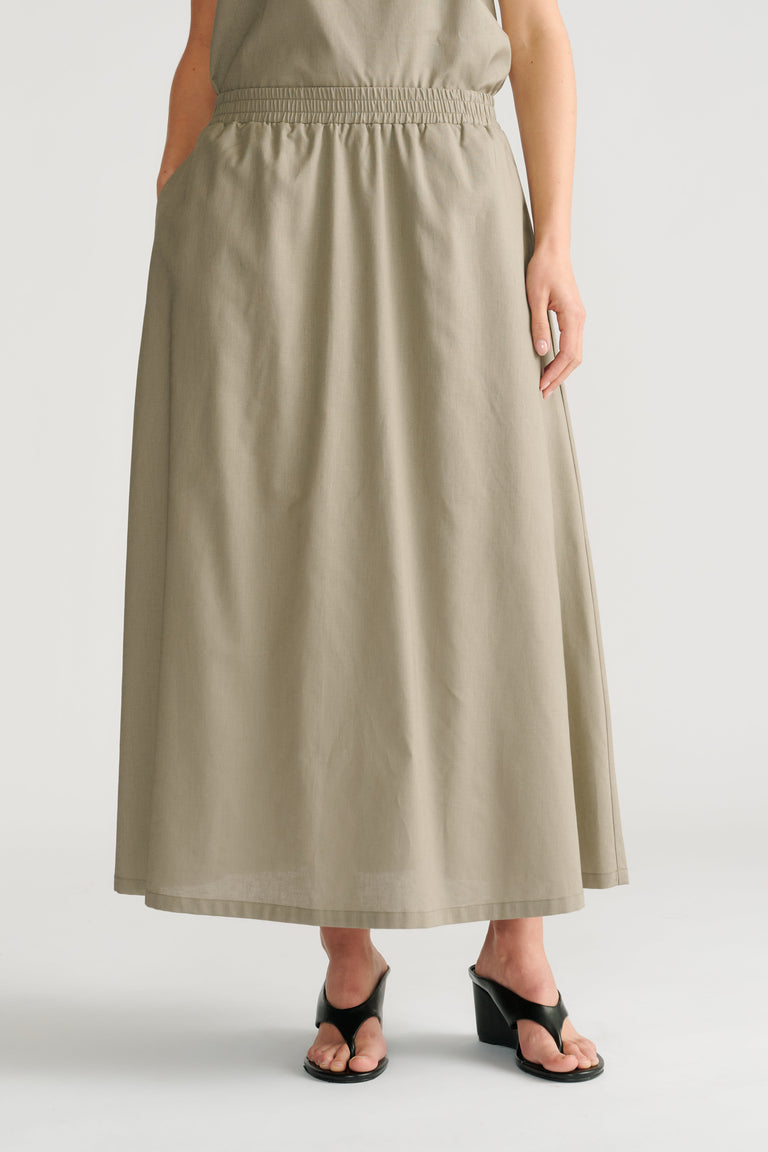 Woman wearing a relaxed fit sage midi skirt with an elastic waistband paired with black heeled sandals.