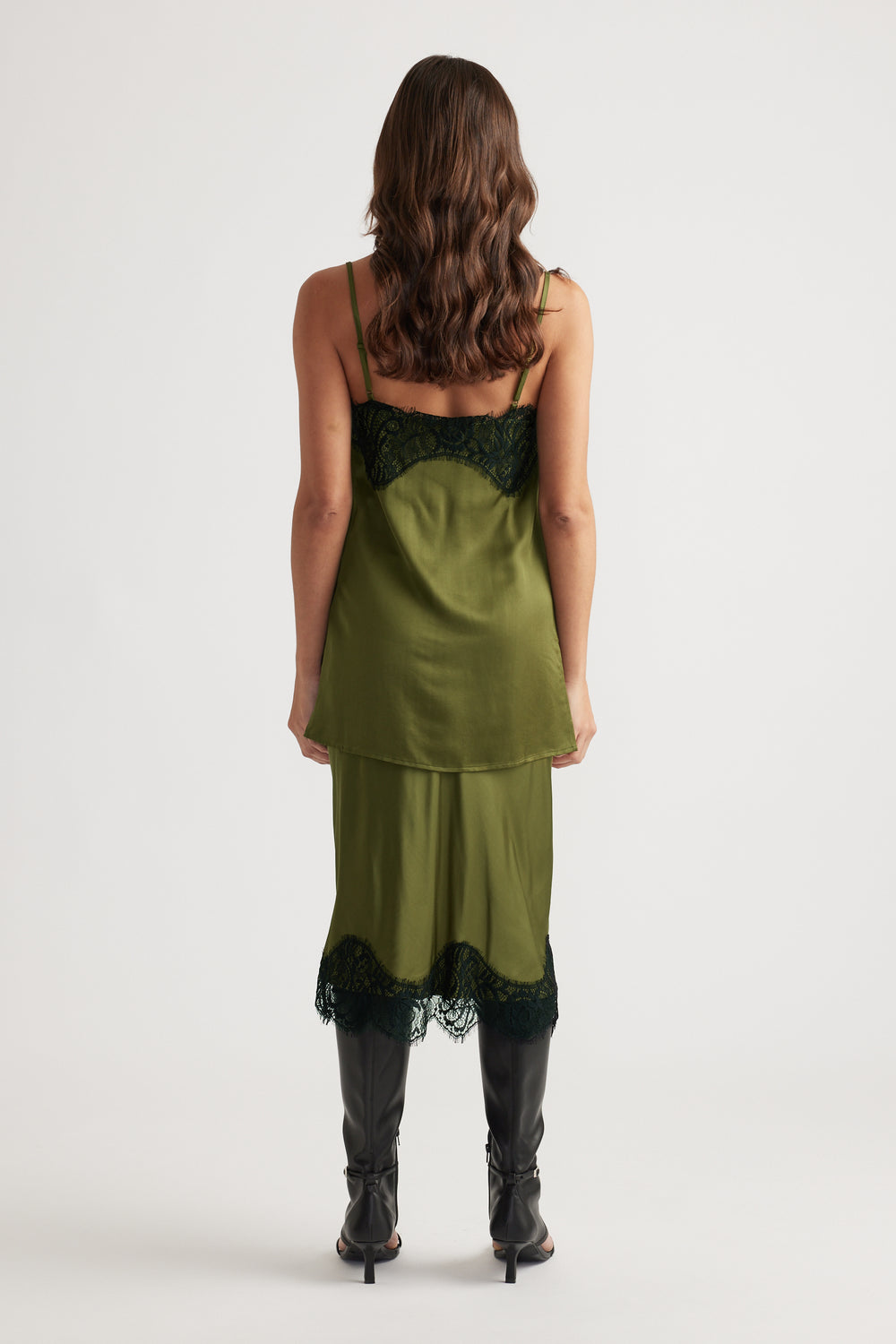 Back view of olive green lace-trimmed slip top and matching skirt paired with black heeled boots
