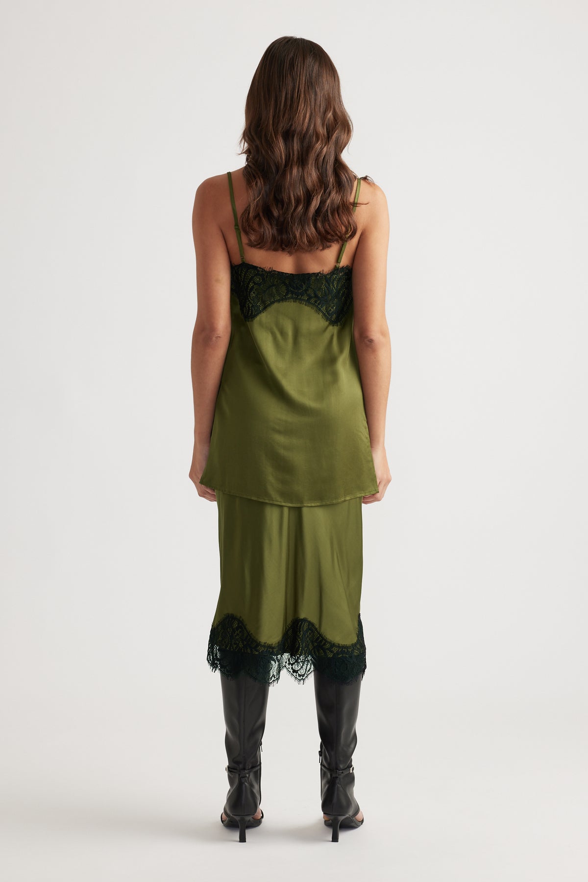 Back view of olive green lace-trimmed slip top and matching skirt paired with black heeled boots