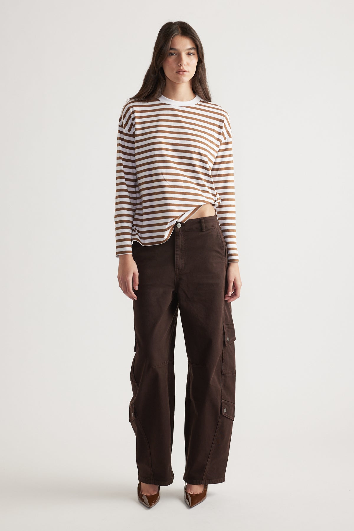 Woman wearing a relaxed brown and white striped long-sleeve top with dark brown wide-leg cargo pants and pointed heels
