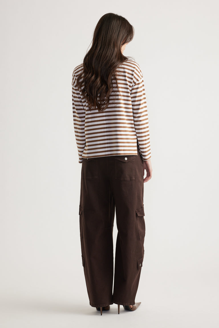 Woman wearing a tan and white striped long sleeve top paired with loose dark brown cargo pants and pointed heels, viewed from behind.