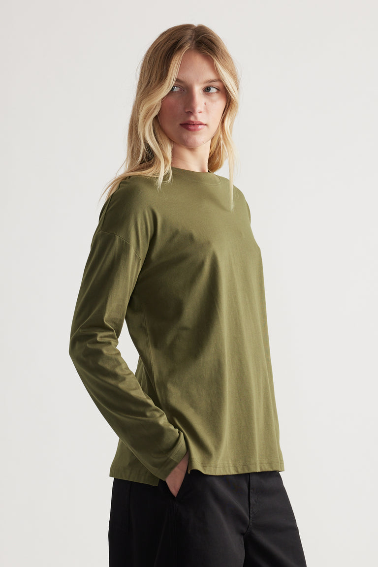Woman wearing an olive green long sleeve crew neck top paired with black pants in a clean, simple style