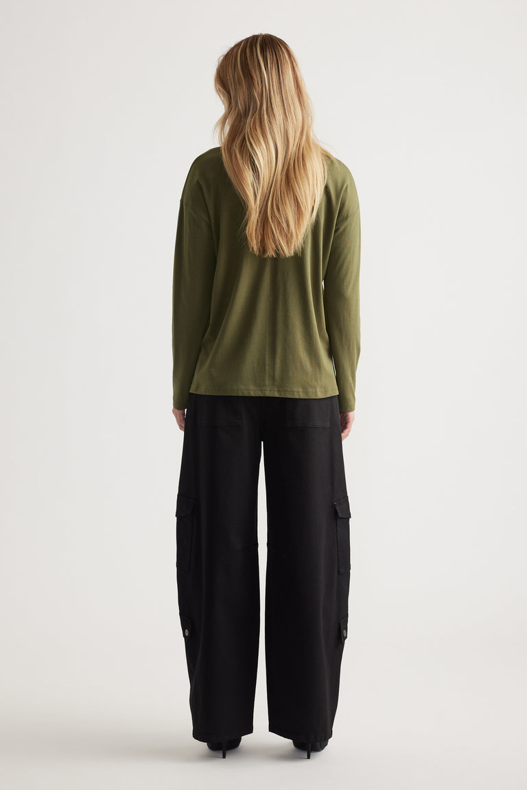 Woman with long blonde hair wearing an olive crew neck long sleeve top paired with wide-leg black cargo pants