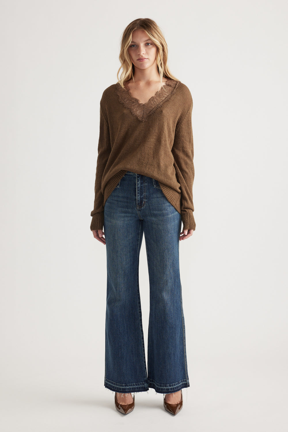 Woman wearing a brown lace-trim V-neck jumper paired with high-waisted wide-leg blue jeans and brown pointed heels