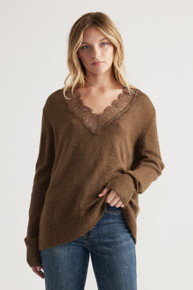 Woman wearing a relaxed brown knit sweater with lace-trimmed V-neck paired with classic blue denim jeans
