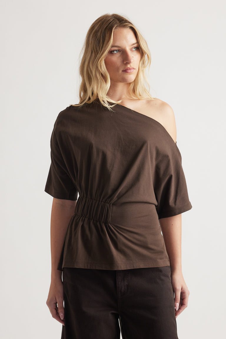 Woman wearing a brown asymmetrical one shoulder tee with a cinched waist