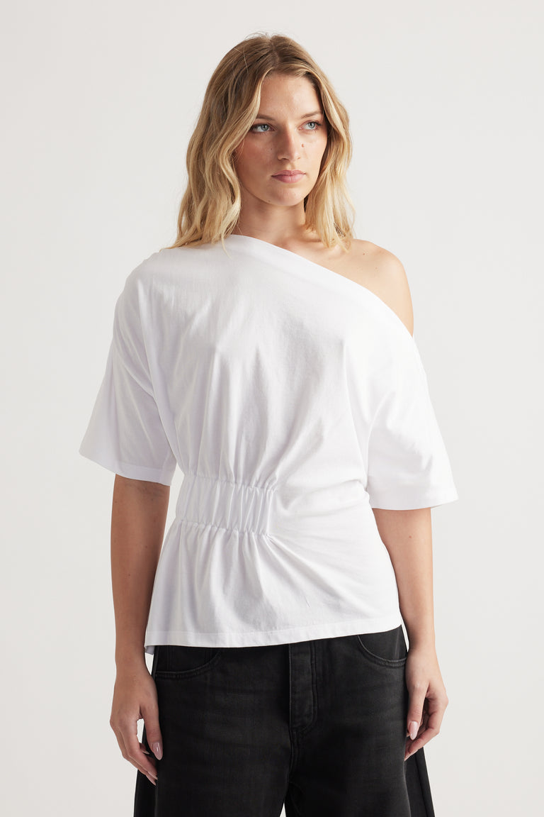 Woman wearing a white asymmetrical neckline tee with a cinched waist and black pants