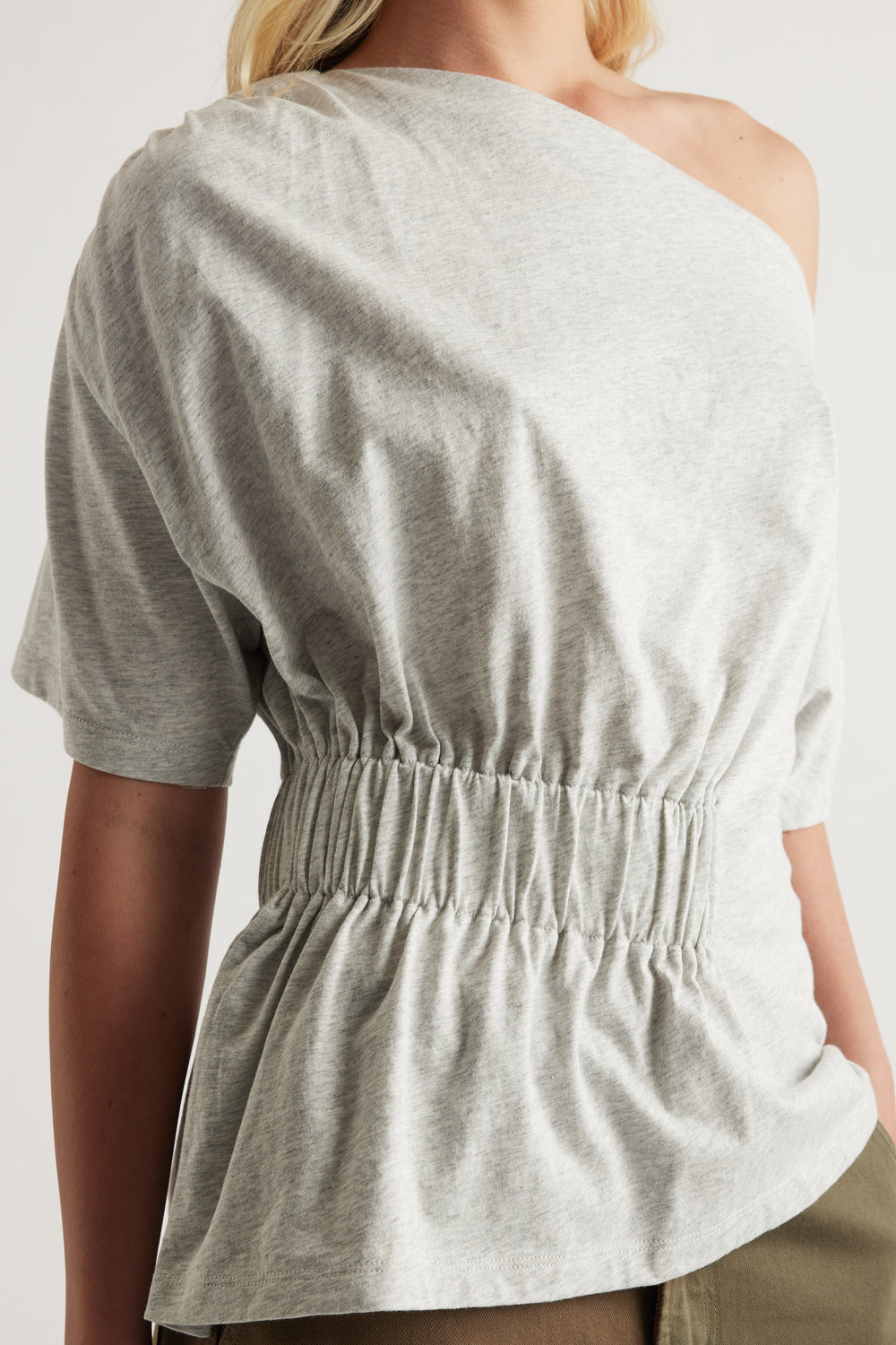 Grey asymmetrical short sleeve top with a one shoulder neckline and elastic cinched waist