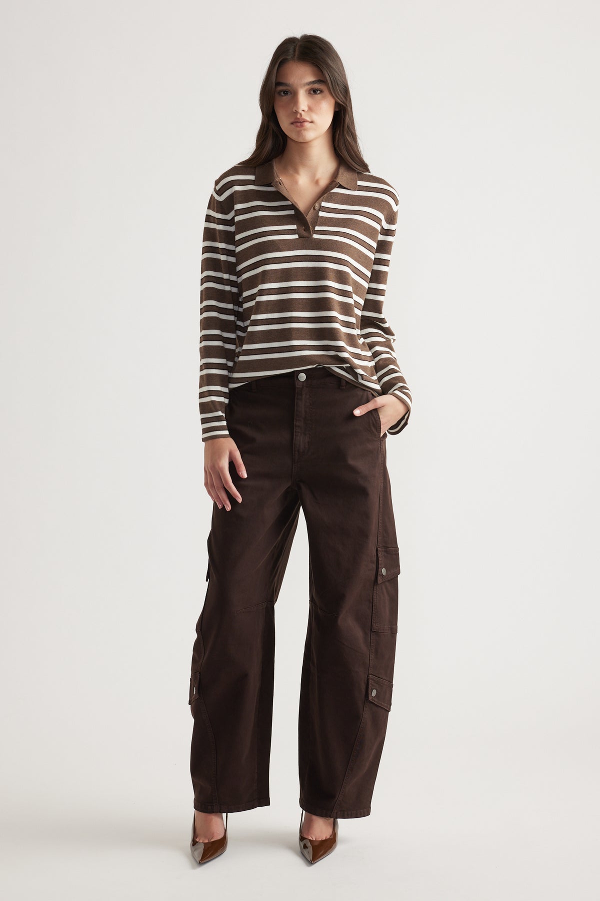 Woman wearing a long-sleeve brown and cream striped knit polo paired with dark wide-leg cargo pants and heels