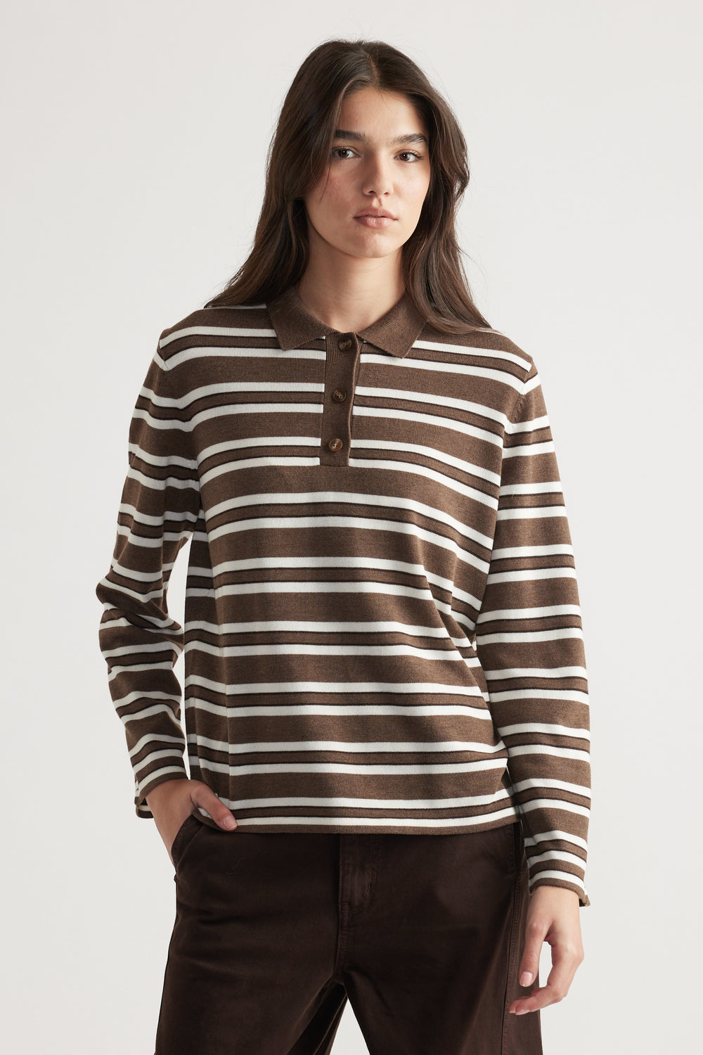 Woman wearing a brown and cream striped knit polo with long sleeves, styled casually with dark trousers