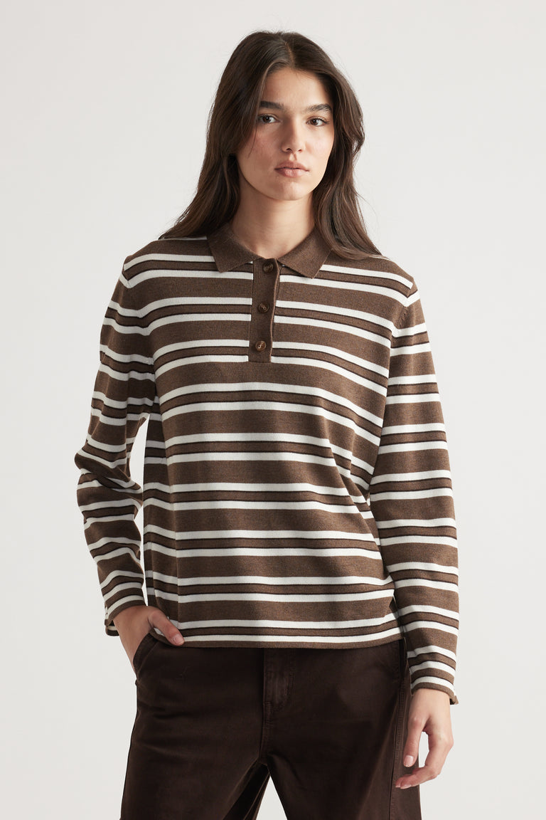 Woman wearing a brown and cream striped knit polo with long sleeves, styled casually with dark trousers