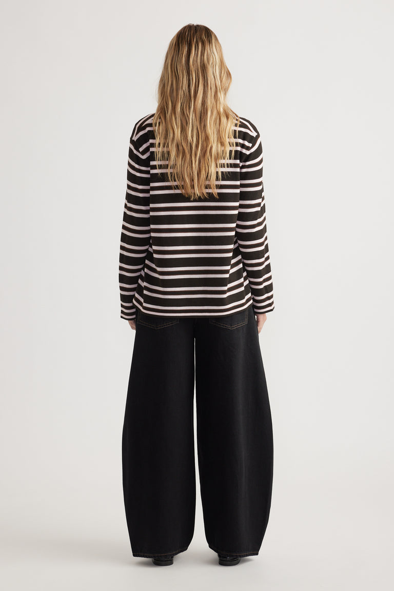 Woman seen from behind wearing a striped long sleeve knit top paired with wide-leg black pants against a white background