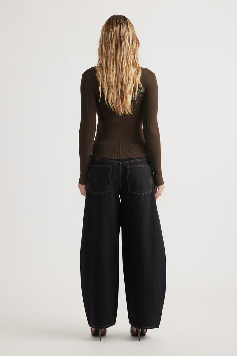 Woman seen from behind wearing a fitted dark brown long-sleeve top and wide-leg black jeans with heels