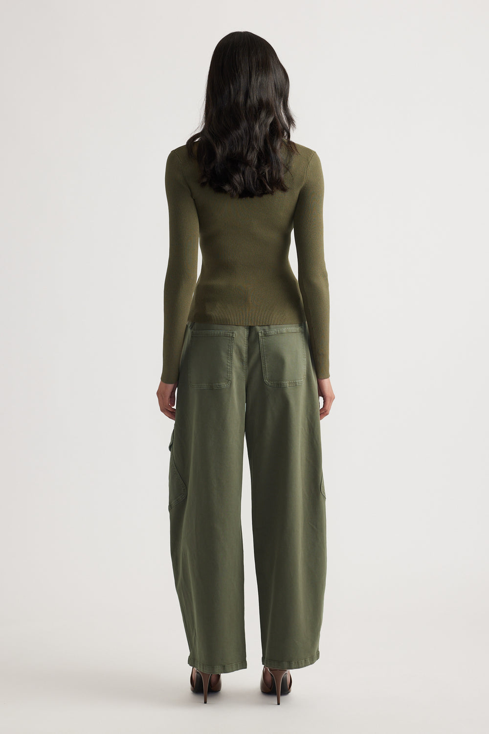 Woman seen from behind wearing a fitted olive long sleeve ribbed top paired with loose olive wide-leg pants