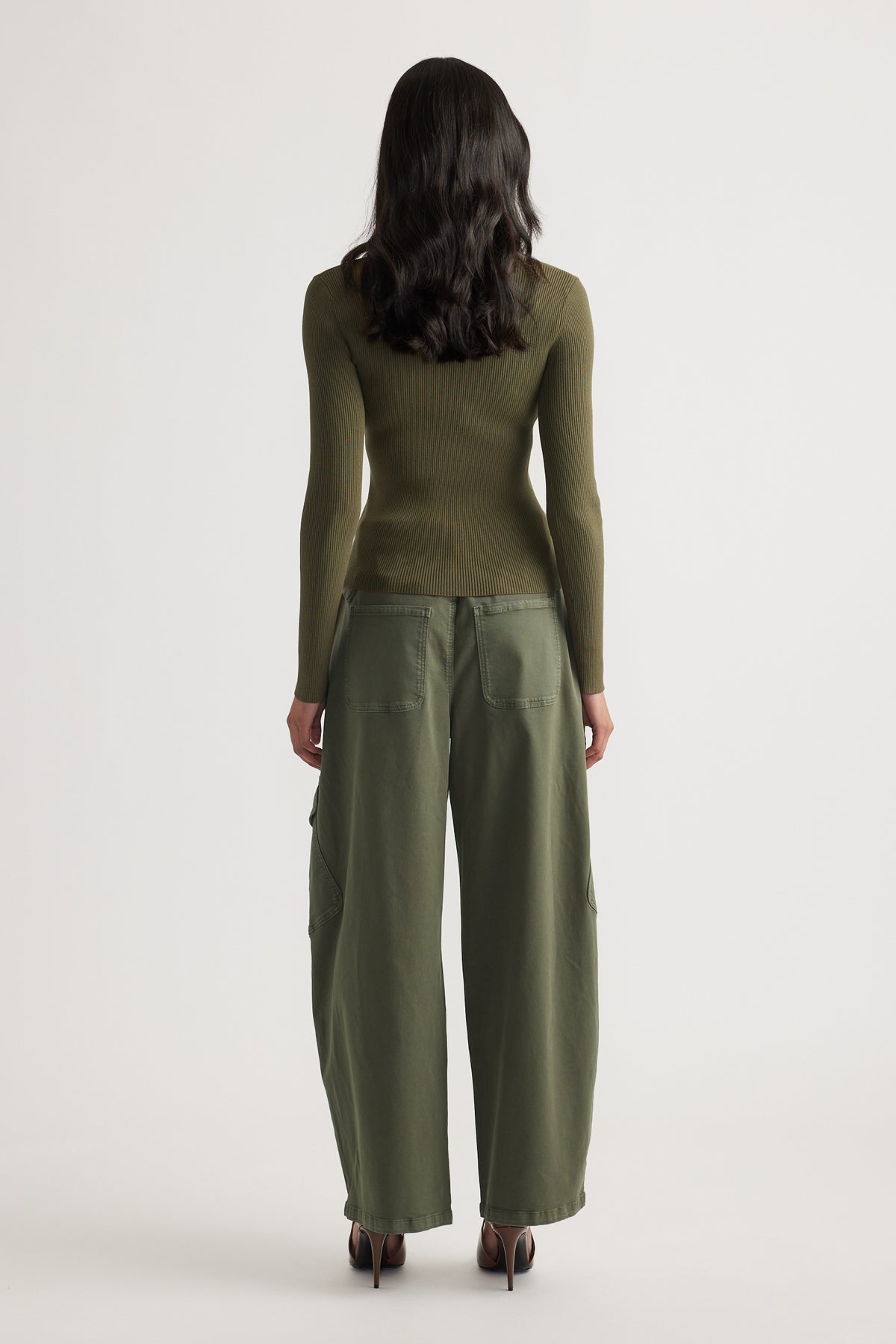 Woman seen from behind wearing a fitted olive long sleeve ribbed top paired with loose olive wide-leg pants