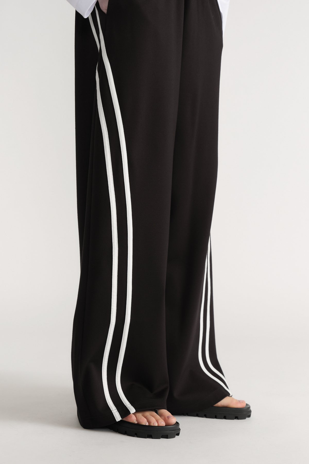 Black wide leg pants with double white side stripes styled with black platform sandals