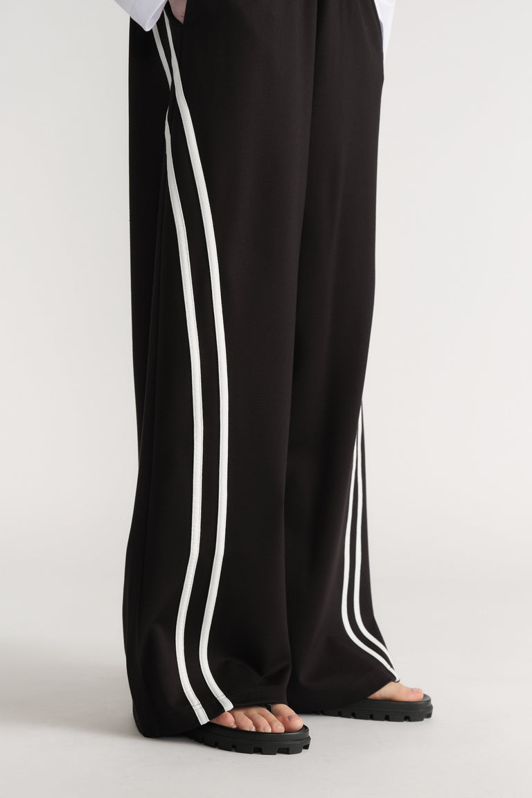 Black wide leg pants with double white side stripes styled with black platform sandals