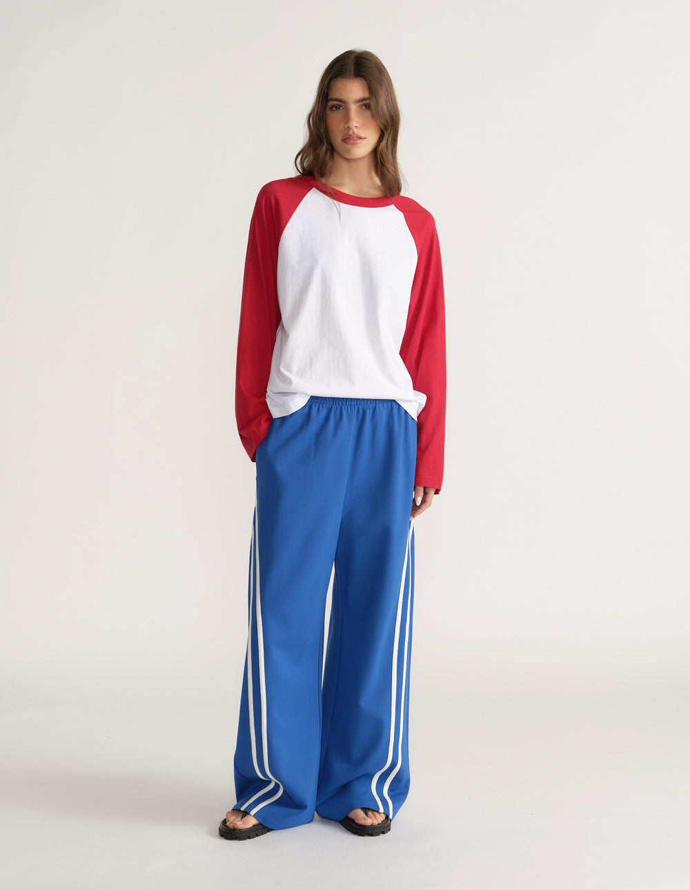 Woman wearing blue wide leg side stripe pants with a red and white raglan top