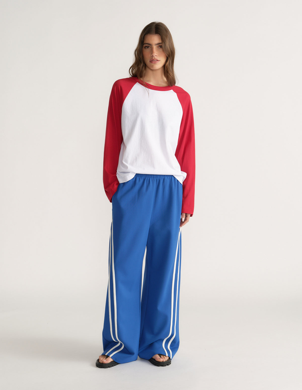 Woman wearing blue wide leg side stripe pants with a red and white raglan top