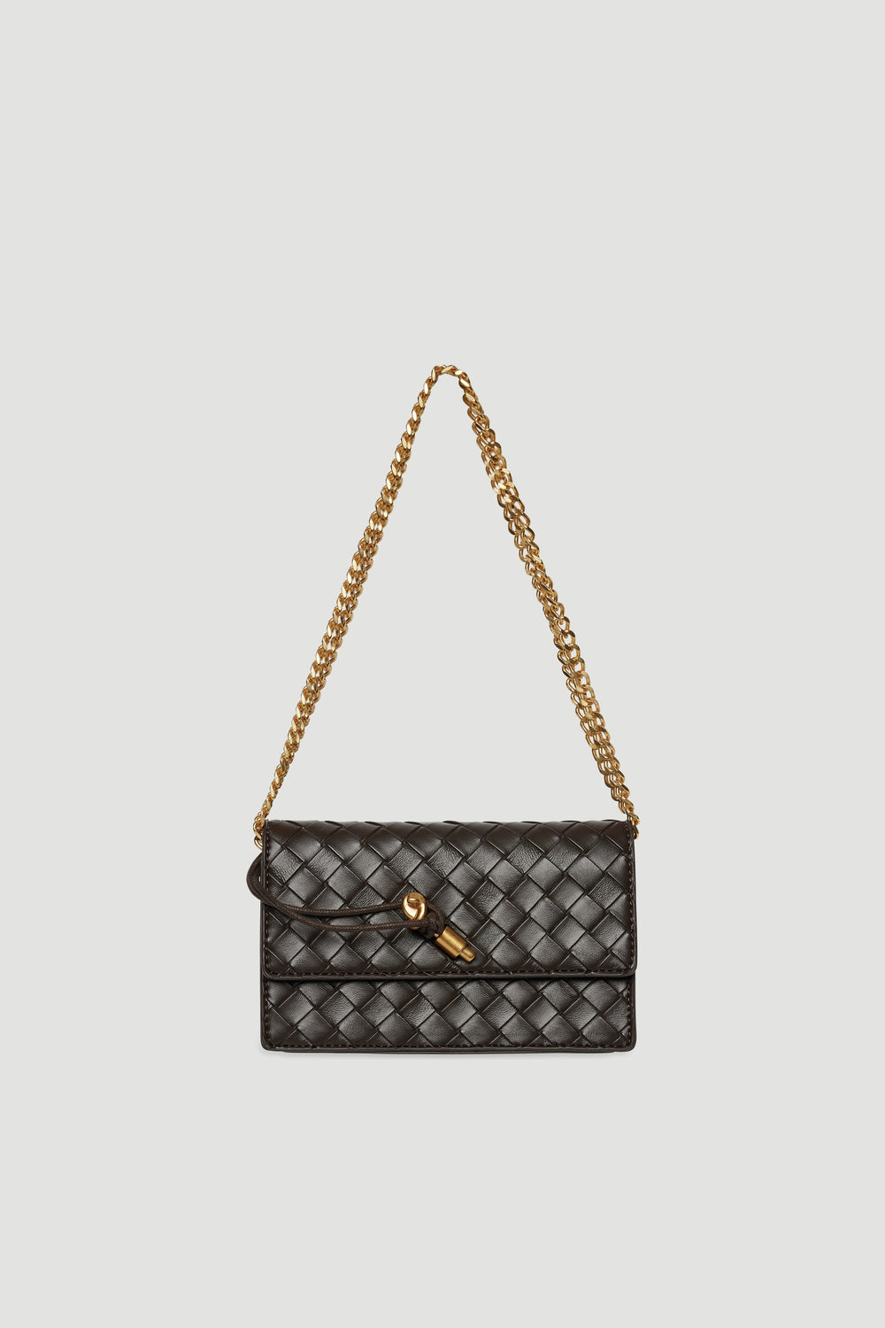 Small dark brown woven crossbody bag with gold chain strap and clasp closure against light background