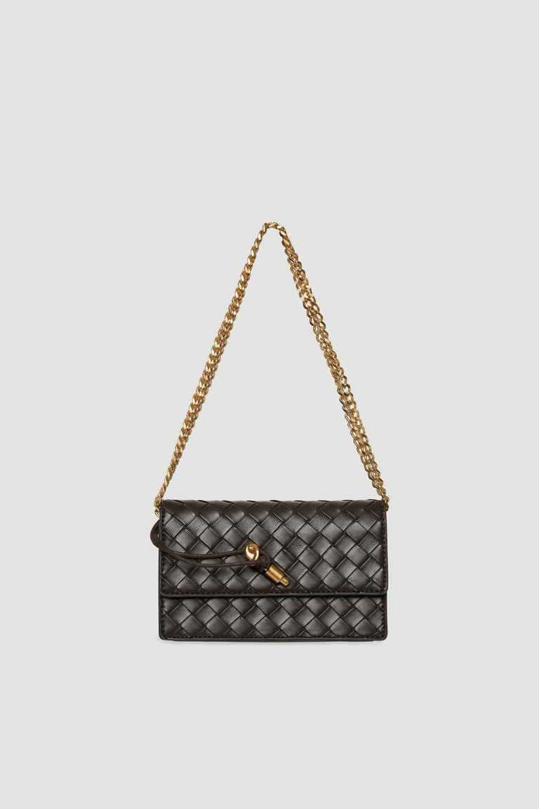 Small dark brown woven crossbody bag with gold chain strap and clasp closure against light background