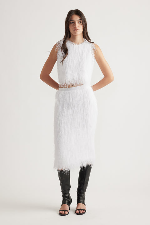 Woman wearing a white textured sleeveless top with matching midi skirt paired with black knee-high heeled boots