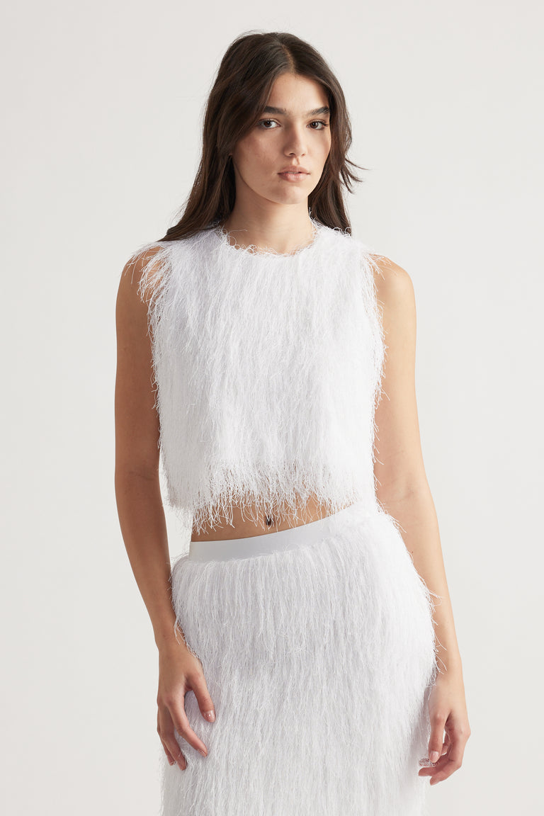 Woman wearing a textured white sleeveless top with fringed detail paired with a matching skirt for a chic look
