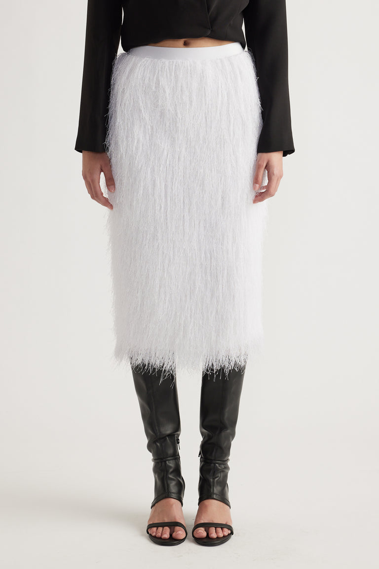 White midi skirt with textured fringe detail styled with black long-sleeve top and knee-high black boots