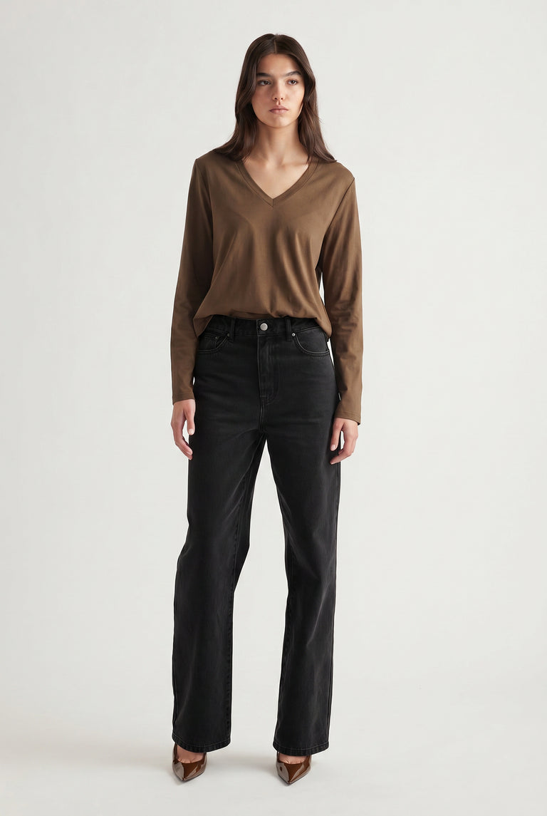 Woman wearing a brown V-neck long sleeve top paired with high-waisted black straight-leg jeans and pointed shoes