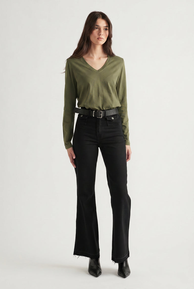 Woman wearing an olive V-neck long sleeve top tucked into high-waisted black flared jeans with a belt and boots